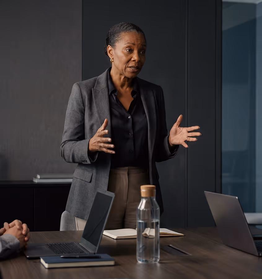 Businesswoman speaking and gesturing with hands during a meeting in a modern office.